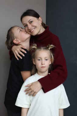 Güzel, genç bir anne, çocuklara sarılıyor, aile bağı kuruyor.