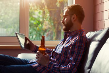 Dijital tablet şişe bira içme ile sakallı adam