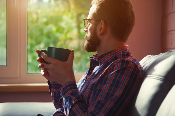 Bearded man sitting with cup of morning coffee or tea and lookin — Stock Photo, Image