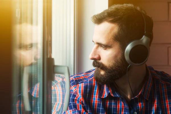 Стильный бородатый мужчина в наушниках слушает музыку возле Уиндо — стоковое фото