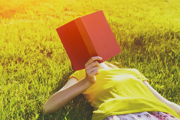 Menina leitura livro deitado na grama — Fotografia de Stock