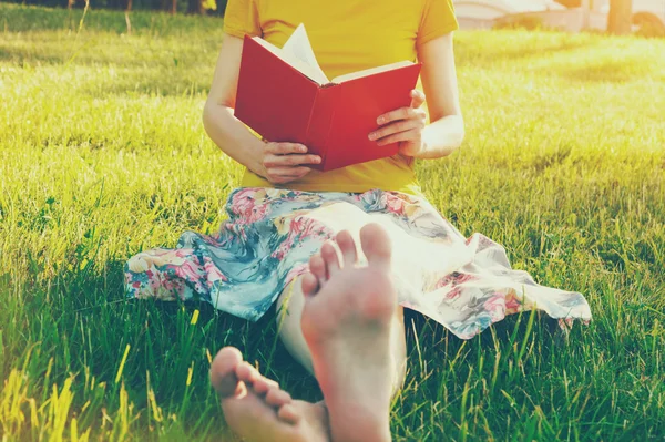 Дівчина читає книгу, що лежить босоніж — стокове фото