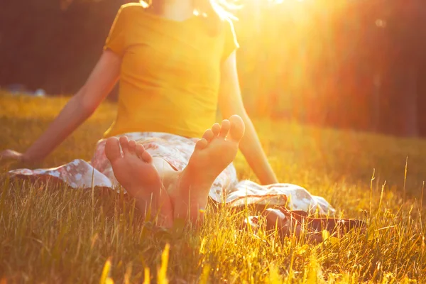 Meisje zit in gras barefoot — Stockfoto