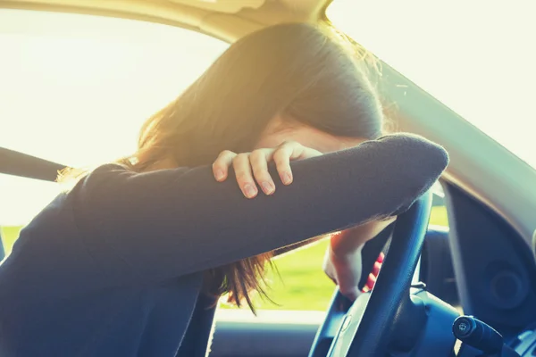 Stressed or tired girl in car lying on steering wheel — Stock Photo, Image