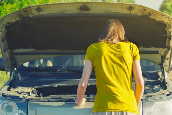 Dziewczyna patrząc pod maską samochodu — Zdjęcie stockowe