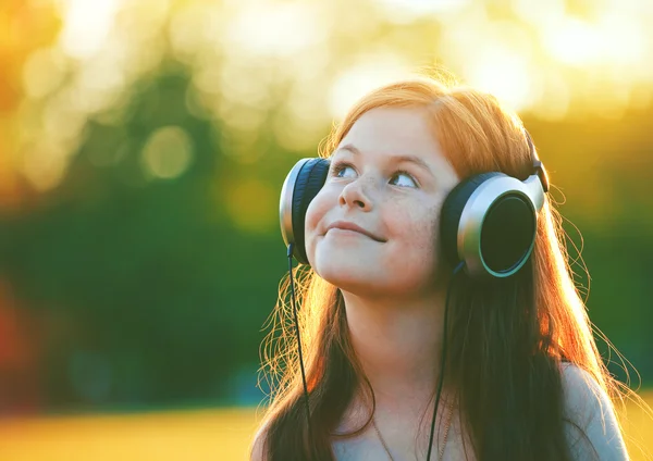 Roodharige meisje met hoofdtelefoons — Stockfoto