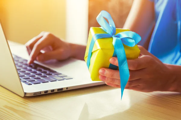 Mani con scatola regalo e laptop — Foto Stock