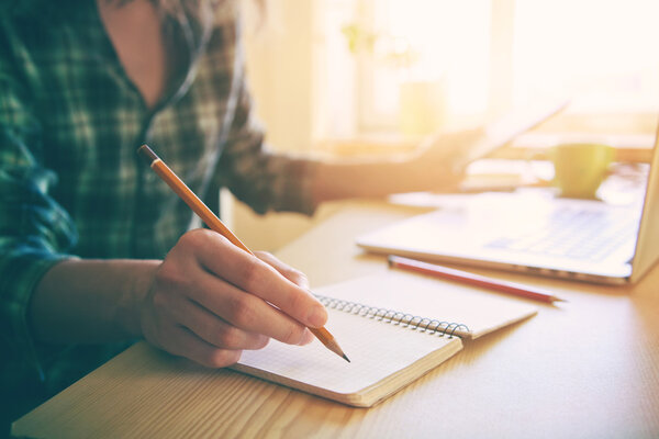 hand with pencil and notebook at workplace