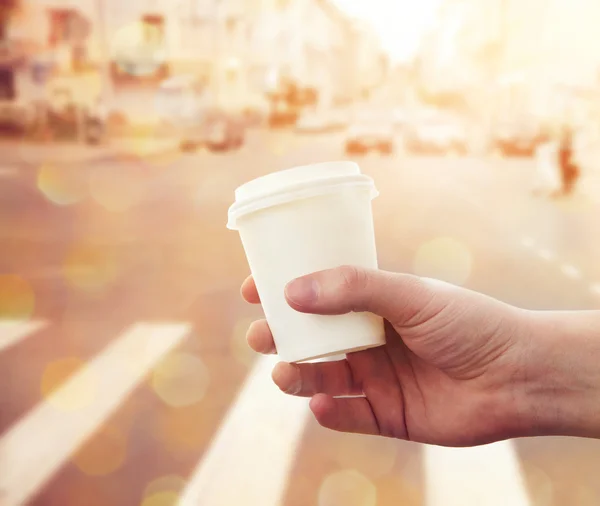 Mão segurando copo de papel com café take-out na rua da cidade — Fotografia de Stock