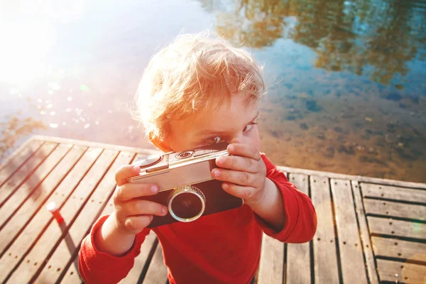 Retrato de um menino bonito sorridente tirando foto com câmera retro — Fotografia de Stock