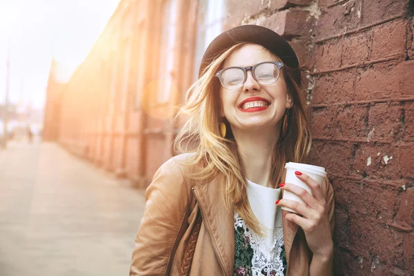 Mujer alegre en la calle bebiendo café de la mañana bajo el sol —  Fotos de Stock