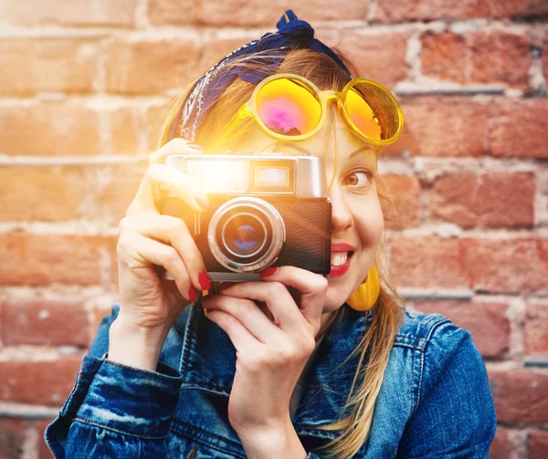 Usměvavá dívka s vinobraní fotoaparát s foto s bleskem na bric — Stock fotografie