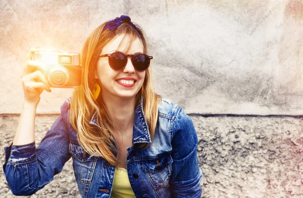 Usměvavá dívka s vinobraní fotoaparát s foto s bleskem na zdi — Stock fotografie