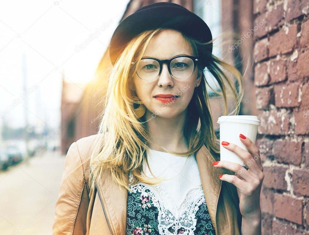 Stylish woman in the street drinking morning coffee