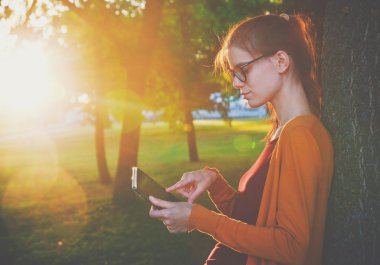 Dijital tablet pc Parkı'nda yaz gün batımı ışık tutan kız