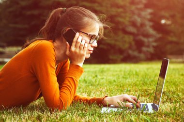 çim yalan ve dizüstü ve akıllı telefon kullanan kız