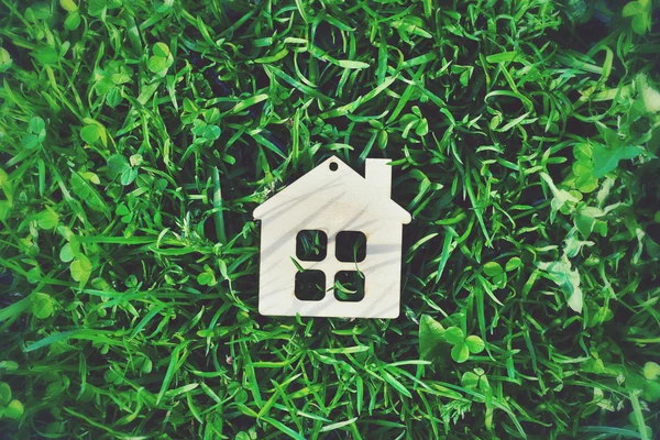 Casa de madeira como símbolo na grama verde — Fotografia de Stock
