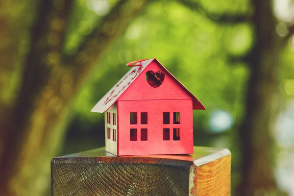 Czerwony model domu jako symbol na naturalny ogród tło — Zdjęcie stockowe