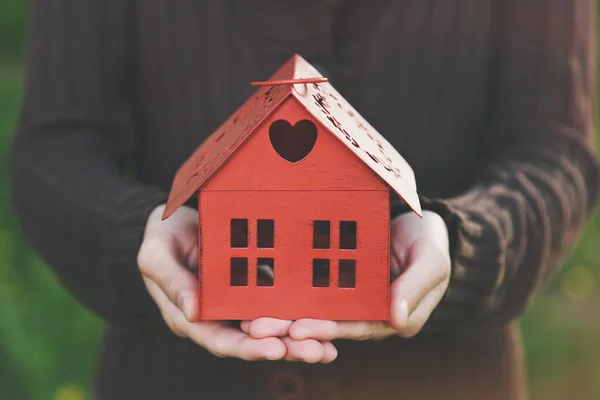 Händer som håller röd modell av huset som symbol — Stockfoto