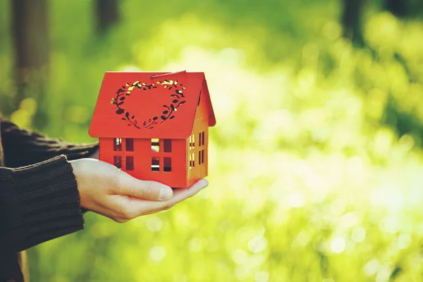 Manos sosteniendo el modelo rojo de la casa como símbolo — Foto de Stock