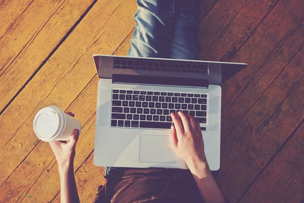 Bärbar dator och papper kopp kaffe i flickor händer — Stockfoto