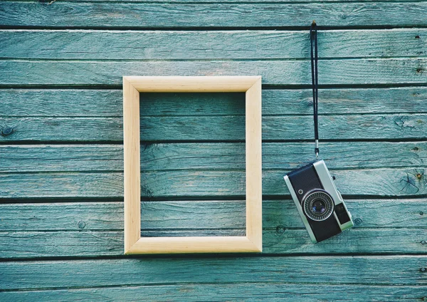 Cámara retro y marco vacío de madera colgando en tableros de madera — Foto de Stock