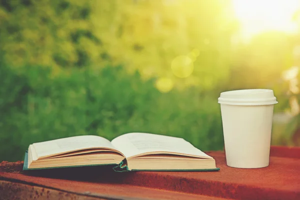Papieren kopje koffie en boeken in het groene gras — Stockfoto