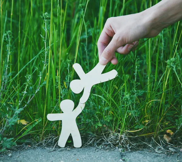 Kleine Männer aus Holz halten Händchen im Sommergras. — Stockfoto