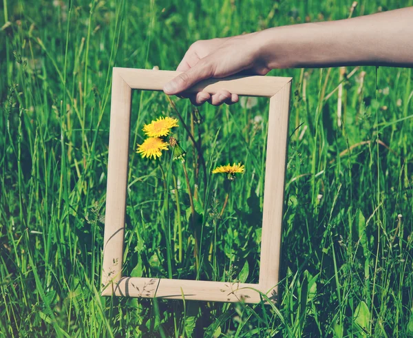 Hand met een houten frame op zonsopgang hemelachtergrond — Stockfoto