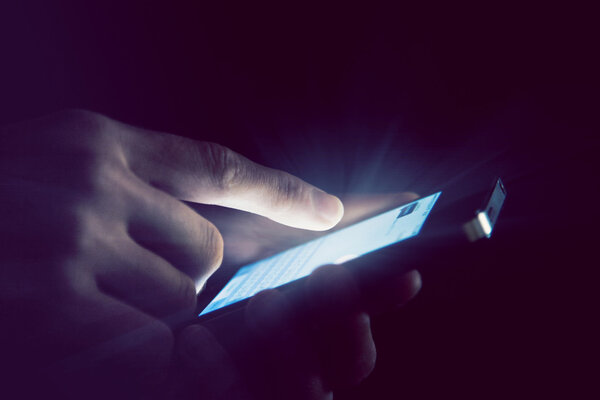 Hands holding and using smartphone in night light