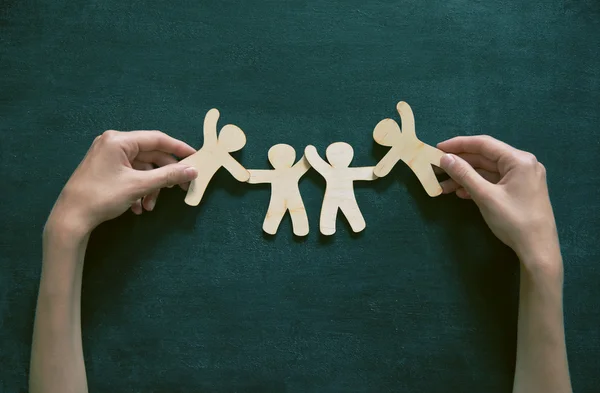 Houten mannetjes hand in hand op blackboard achtergrond. — Stockfoto