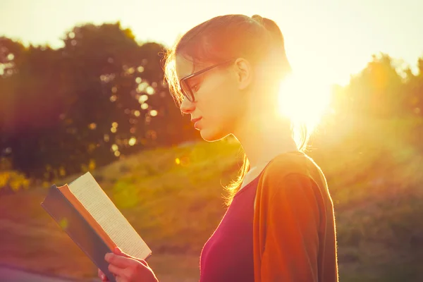 Menina leitura livro no verão pôr do sol luz — Fotografia de Stock