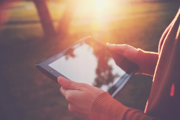 Mãos segurando tablet digital pc na luz do pôr do sol verão — Fotografia de Stock