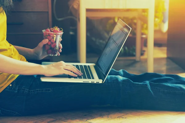 Mains en utilisant un ordinateur portable et en tapant avec un verre de fraise — Photo