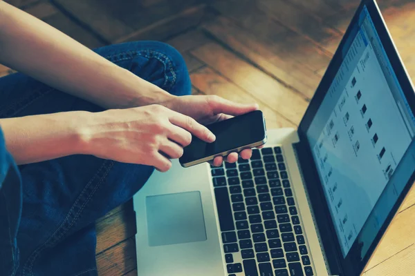 Hands holding smart phone connecting with laptop — Stock Photo, Image