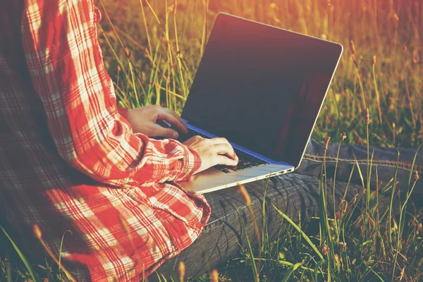 Händerna använder laptop och skriva i sommar gräs — Stockfoto