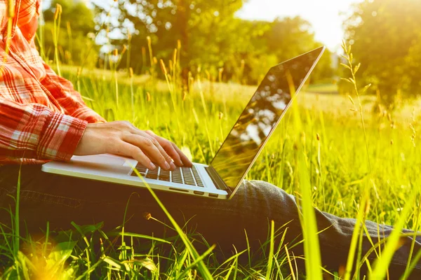 Ręce za pomocą laptopa i wpisując w lecie trawy — Zdjęcie stockowe