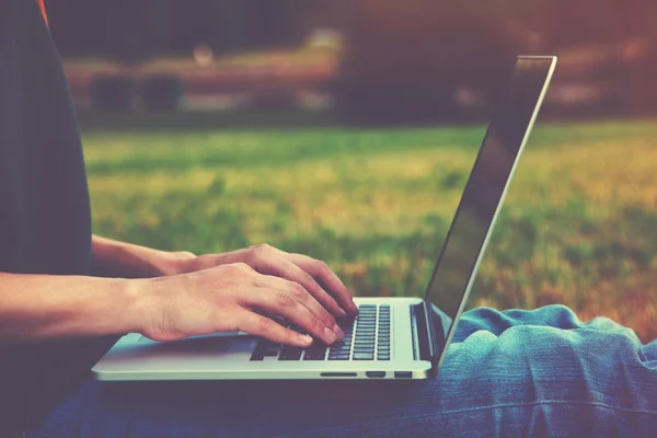Händerna använder laptop och skriva utanför på natur bakgrund — Stockfoto