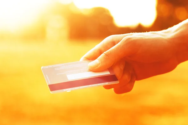 Hand hält Kreditkarte im Sonnenlicht — Stockfoto