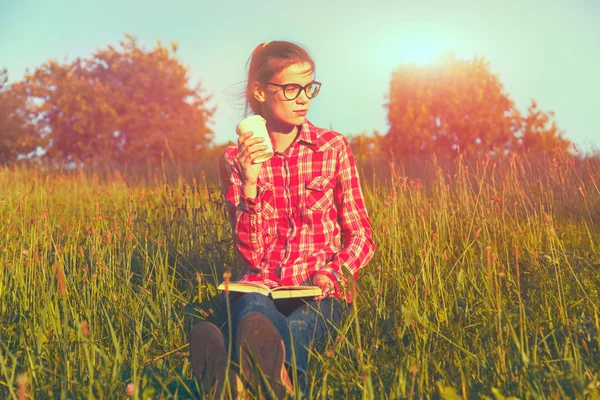 Menina com xícara de café e livro desfrutando na grama de verão — Fotografia de Stock