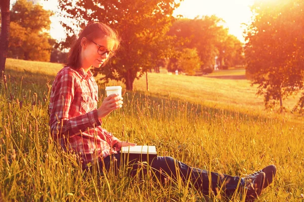 Ragazza con tazza di caffè e libro godendo in erba estiva — Foto Stock