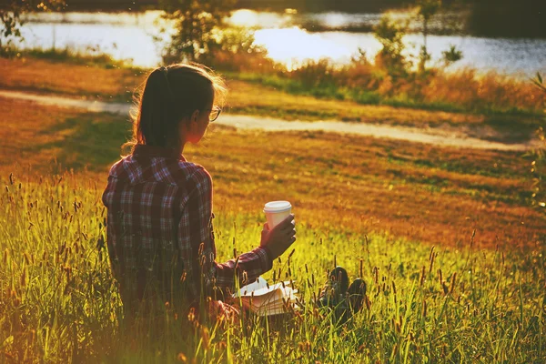 Fille avec tasse de café et livre profiter sur la rive d'été de la rivière — Photo