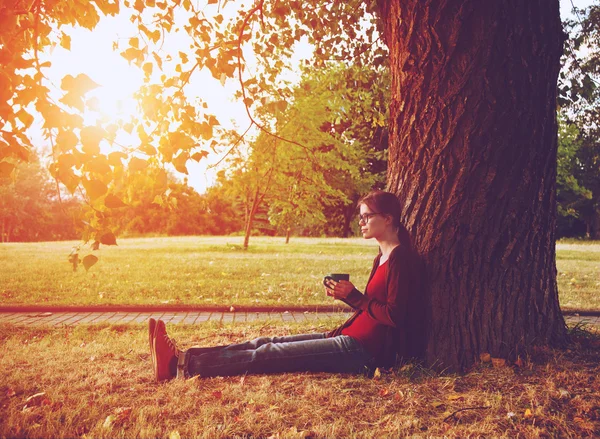 Çay veya kahve park ağacın yanında zevk ile gülümseyen kız — Stok fotoğraf