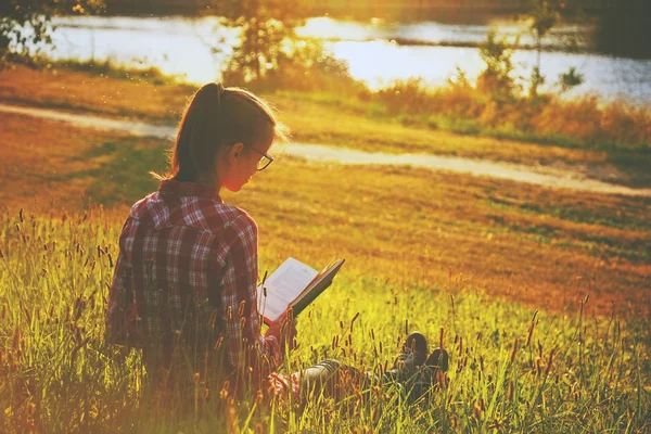 Mädchen liest Buch am Ufer des Flusses — Stockfoto