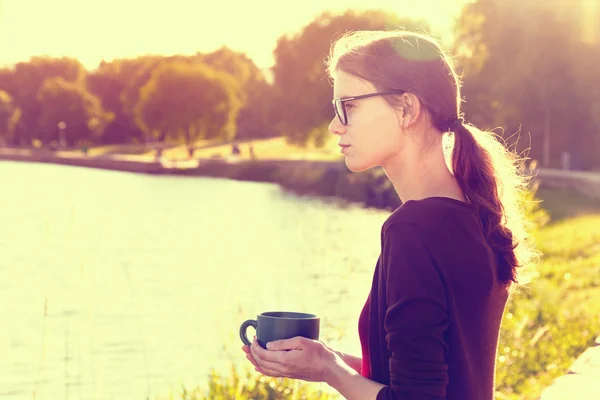 Lachende meisje met een kopje thee of koffie genieten op zomer kust — Stockfoto