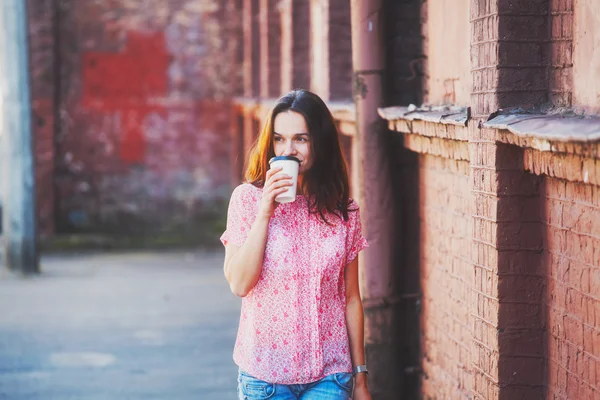 Χαμογελώντας όμορφο κορίτσι περπατώντας στο δρόμο με τον πρωινό καφέ — Φωτογραφία Αρχείου