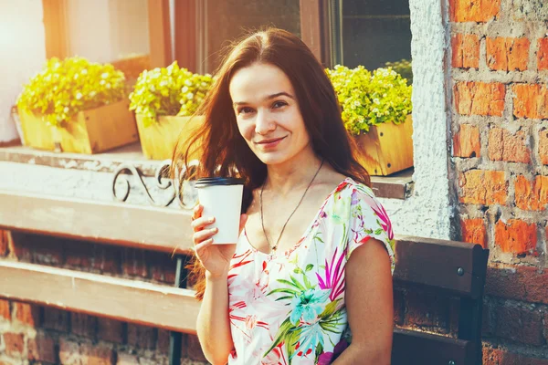 漂亮小女孩微笑着坐在长椅上与早晨喝咖啡 — 图库照片