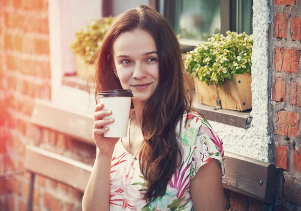 Lächelndes hübsches Mädchen sitzt auf Bank mit Morgenkaffee — Stockfoto