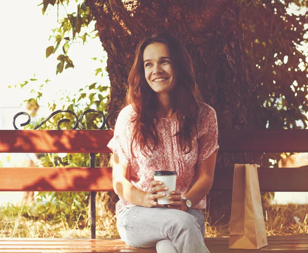 Sorridente bella ragazza seduta sulla panchina con caffè del mattino — Foto Stock