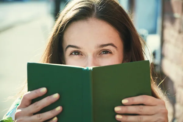 微笑的漂亮女孩抱着本书靠近脸旁 — 图库照片